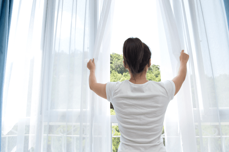 woman opening curtains 